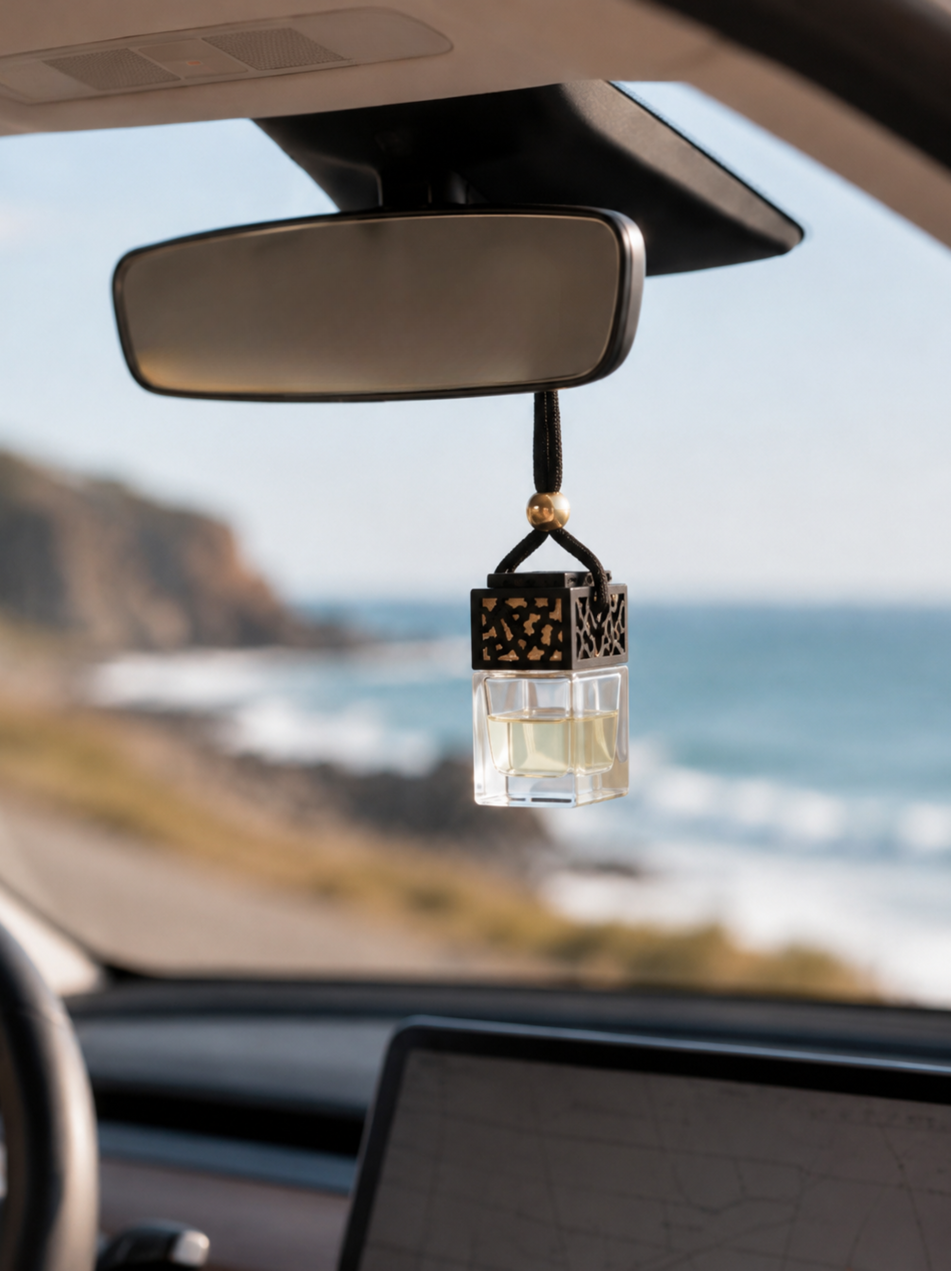 Hanging car fragrance diffuser Free Spirit  on rearview mirror with ocean coastline view in the background