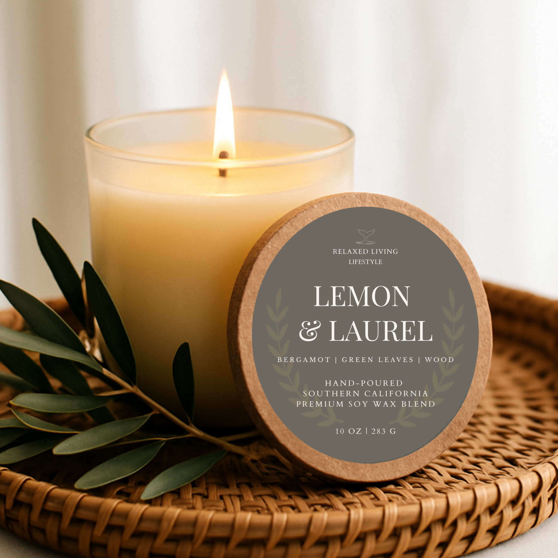 Lemon & Laurel 10 oz Champagne Glass Candle burning and placed in a rattan tray, coastal-inspired home fragrance with citrus and botanical notes