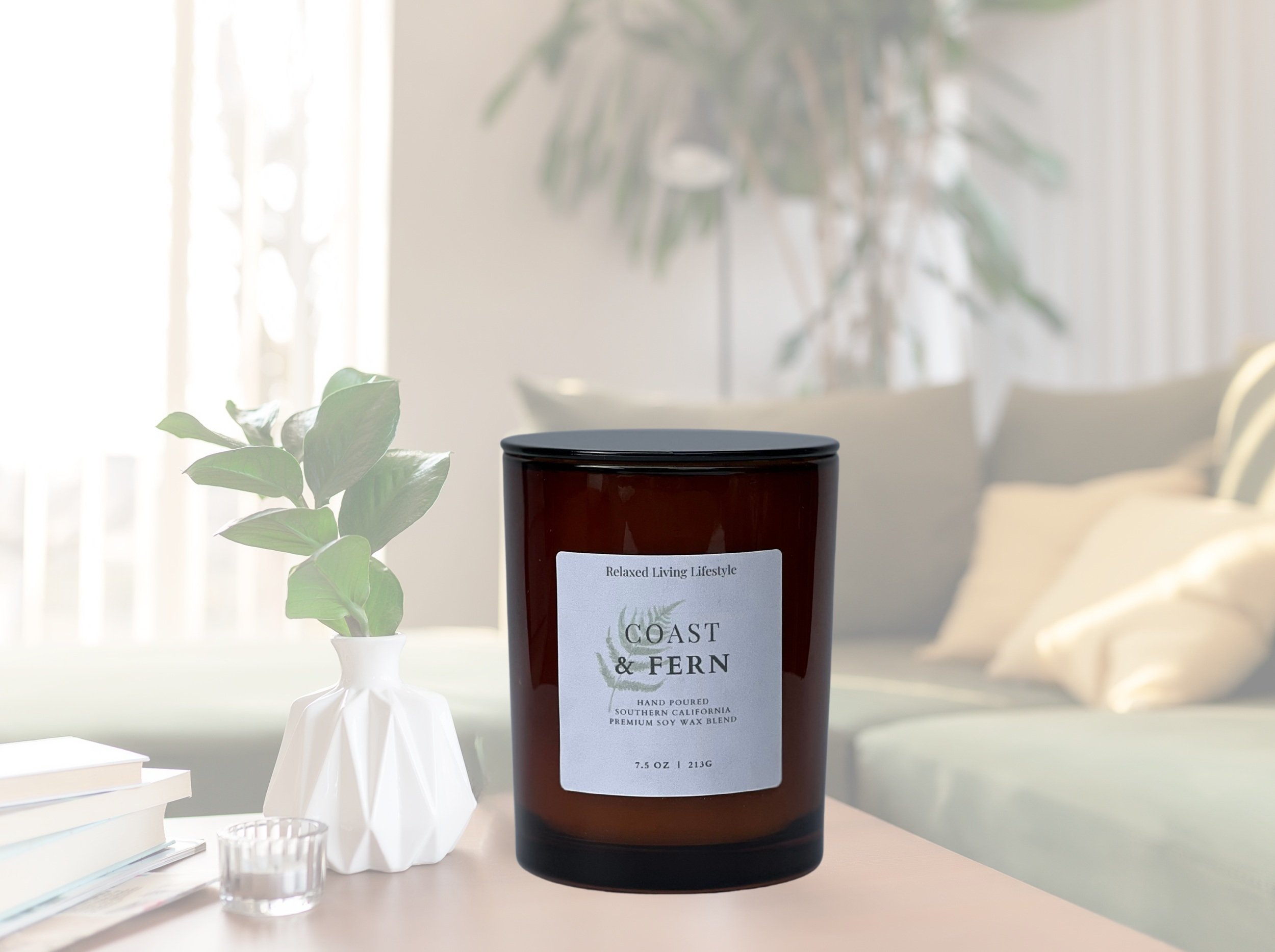 7.5 oz Coast & Fern candle in amber glass vessel with coastal-nature inspired fragrance of ozone, bergamot, lavender, moss, and juniper on a clean natural surface.