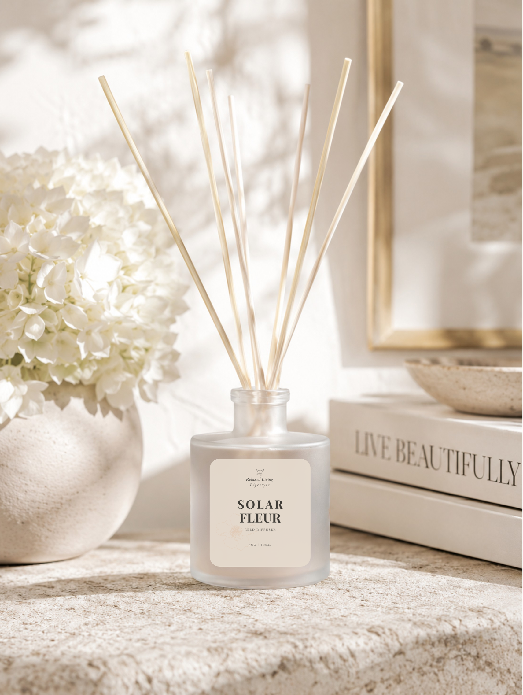 Solar Fleur reed diffuser in a frosted glass vessel displayed on a smooth stone surface with white hydrangeas, stacked neutral books, soft natural sunlight, and elegant window shadows.