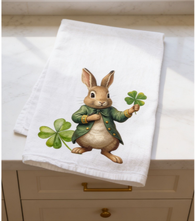 St. Patrick’s Day bunny tea towel displayed on kitchen countertop in flat lay position, cotton spring kitchen towel with four leaf clover design.