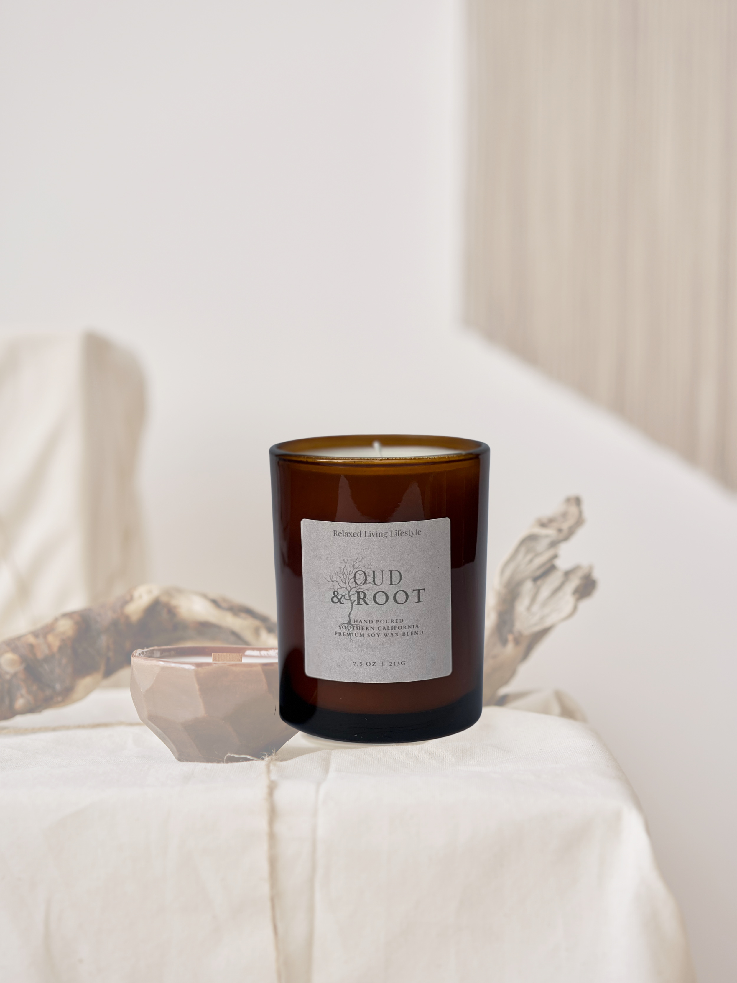 Close up of Oud & Root 7.5 oz candle with earthy, nature-inspired fragrance notes of amaretto, tonka bean, balsam, and oud