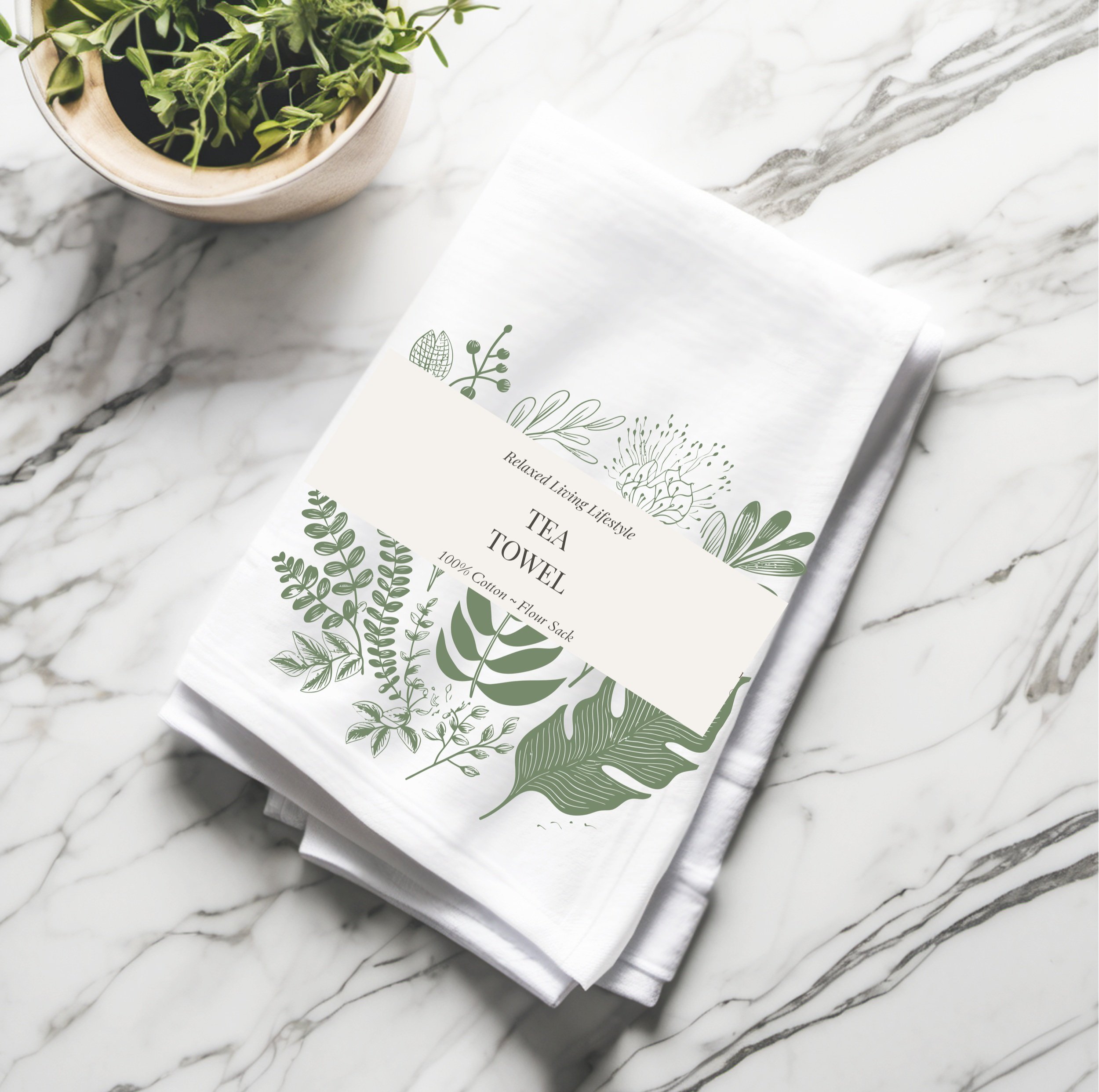 Folded cotton tea towel with watercolor leaf print and branded band, ready for gift giving