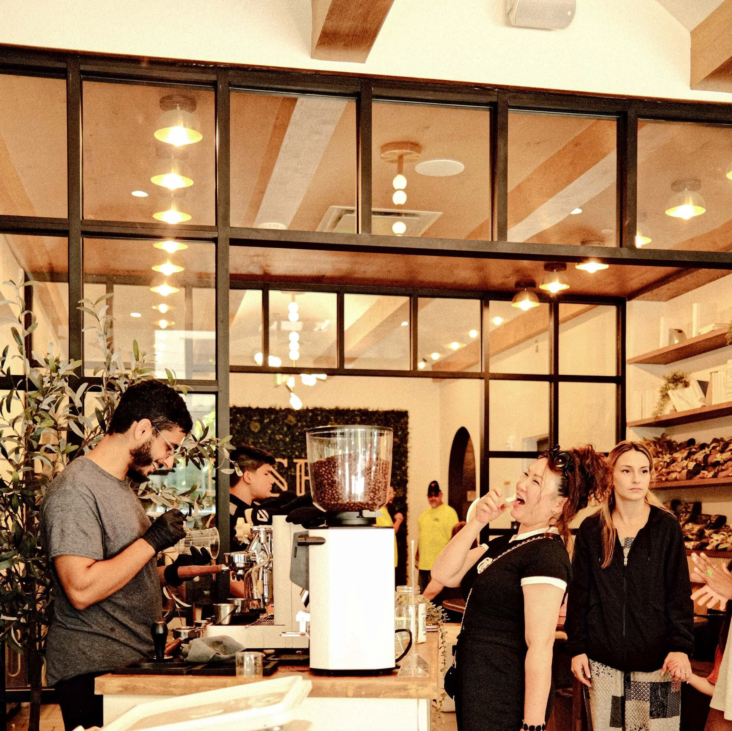 A barista behind a coffee cart makes coffee at an event. The coffee bar has coffee catering equipment for lattes with a happy customer