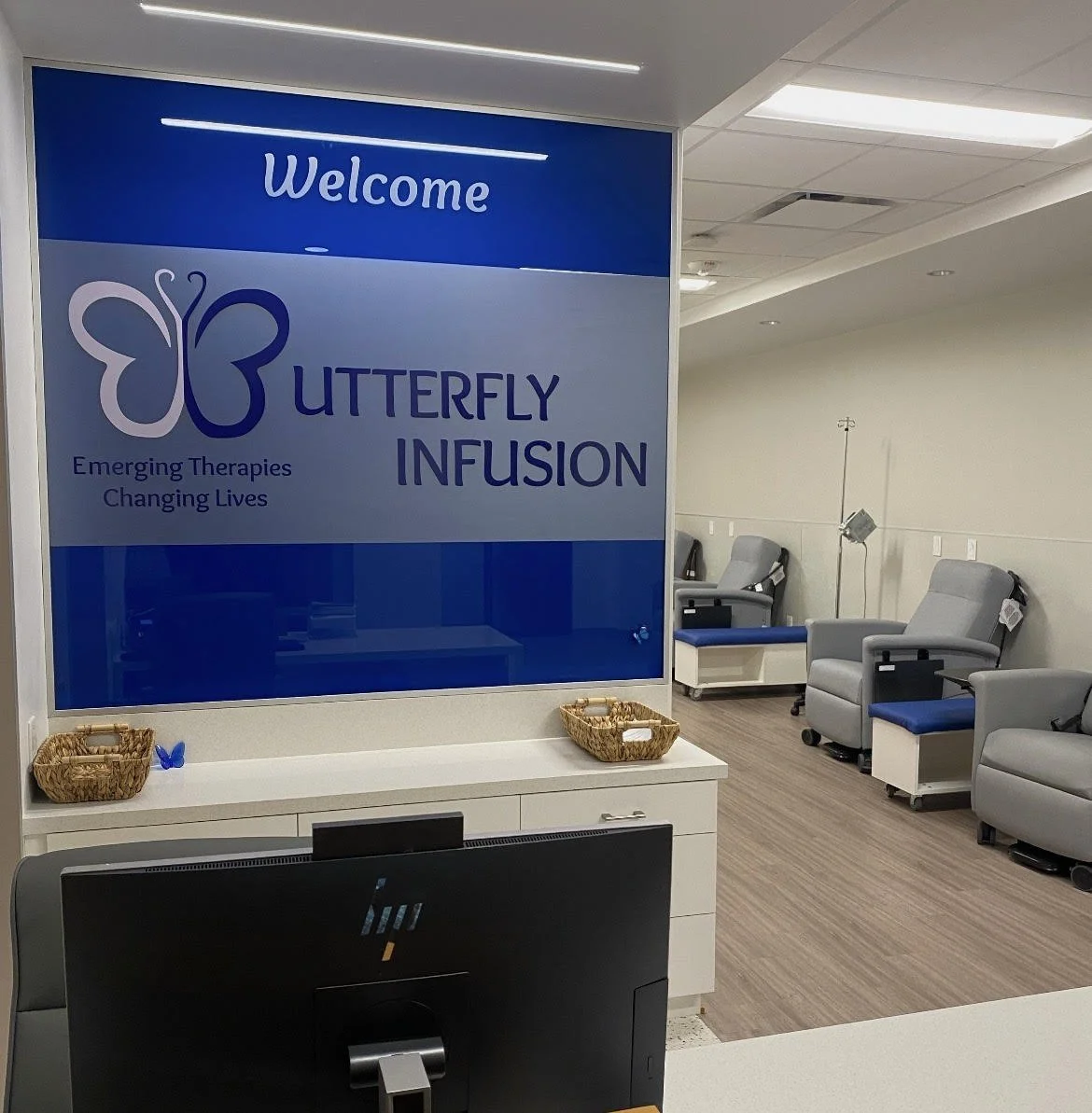 Hospital infusion room with recliner chairs and IV stands, and a welcome sign for Butterfly Infusion.