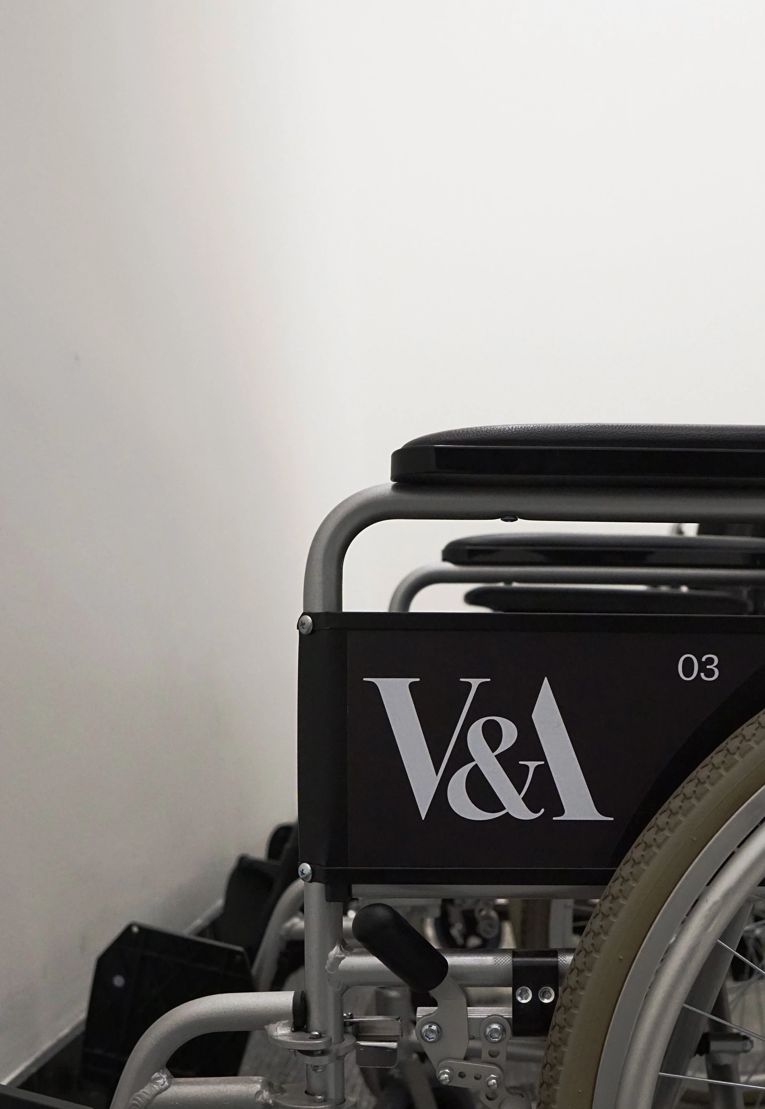 V&A branded wheelchair with number 03 in hallway, partial view.