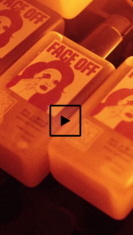 Close-up of a lighter with a 'Face Off' design showing a woman with parted lips and holding her finger to her mouth, in a reddish-orange hue.