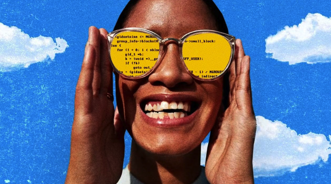 Person smiling while holding sunglasses with yellow code reflected in the lenses, against a bright blue sky with clouds.