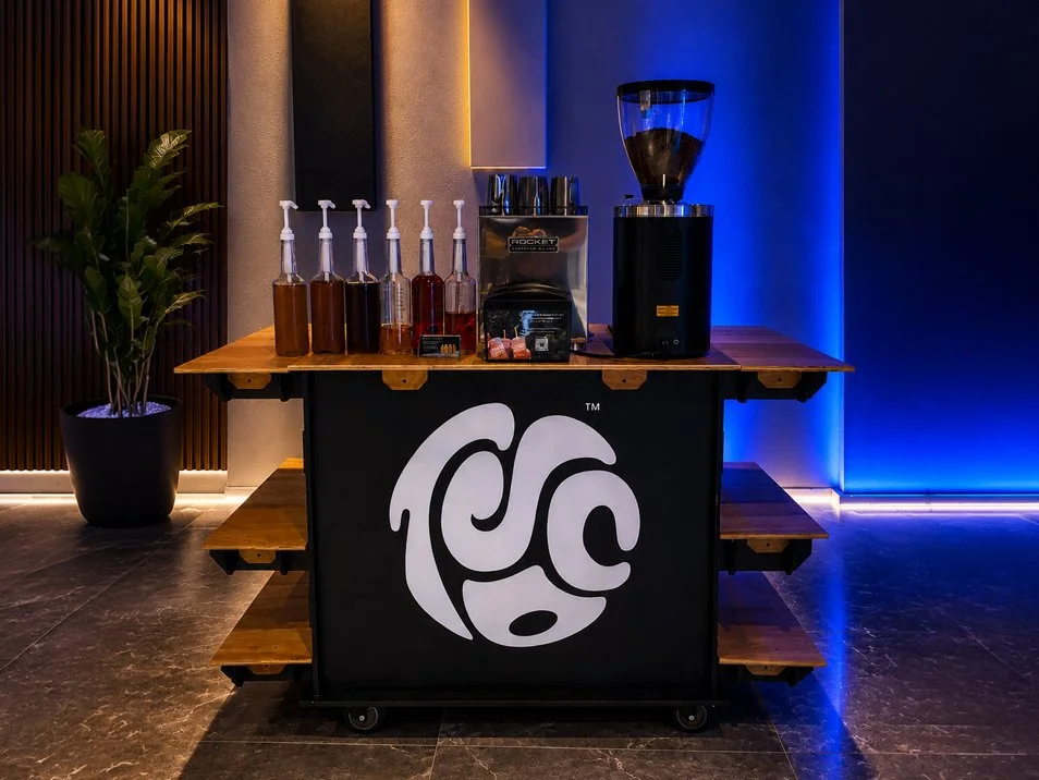 Hand holding a cup of iced tea from Two Straws Co. at a night market, promoting corporate event catering for offices, conferences, schools, churches, and staff appreciation events.