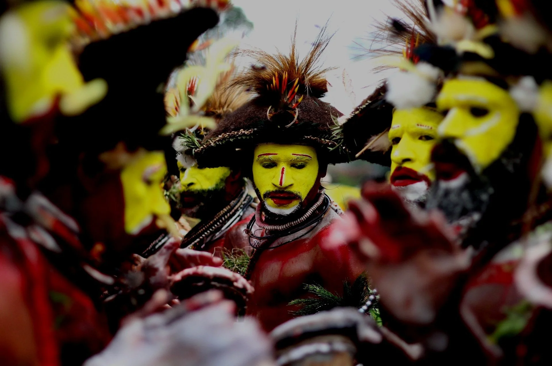 Huli Wigmen in Papua New Guinea wearing bright yellow face paint and traditional human hair wigs during a cultural performance.