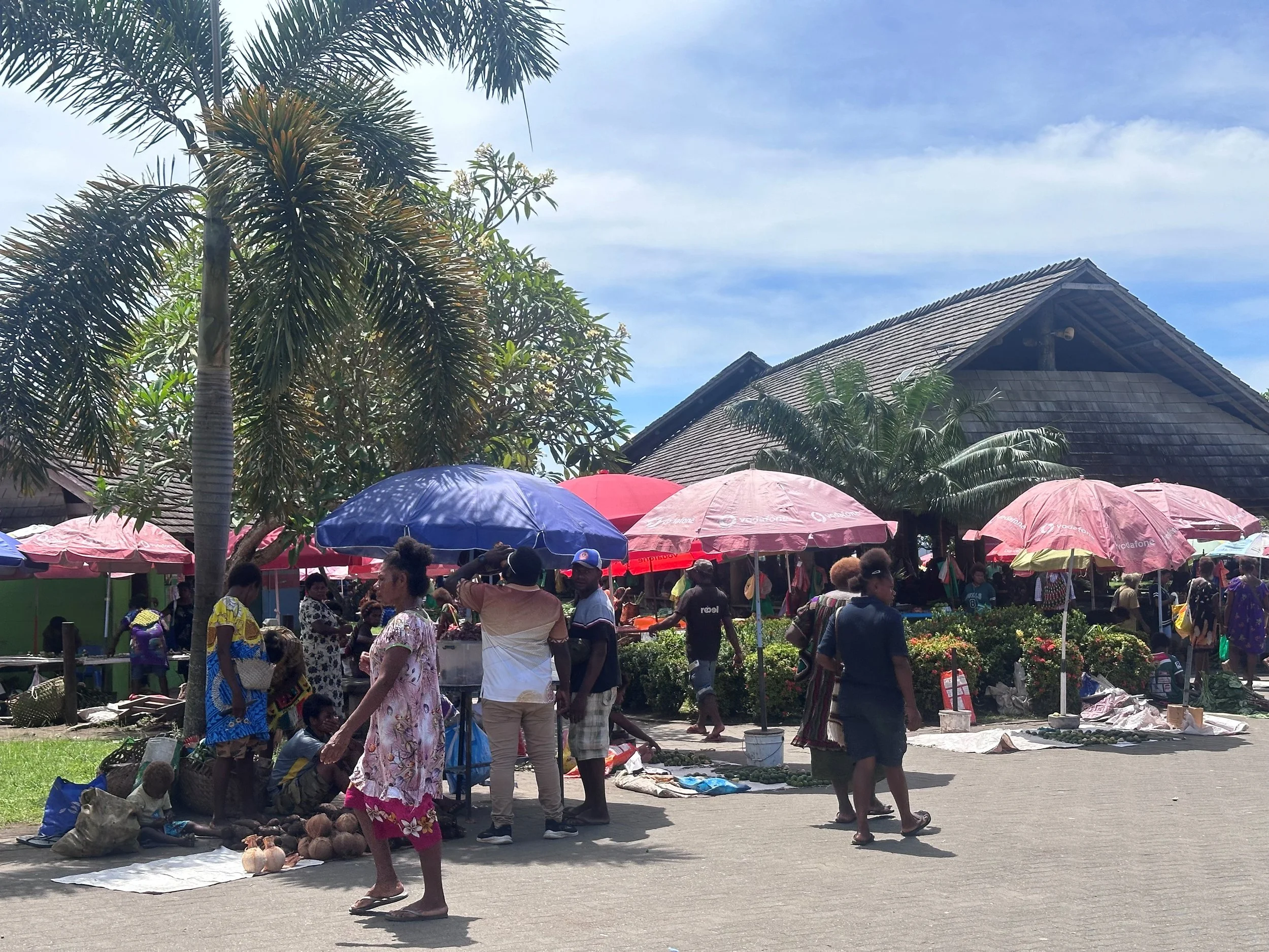 Brightly coloured market umbrella's and tourists chatting with locals
