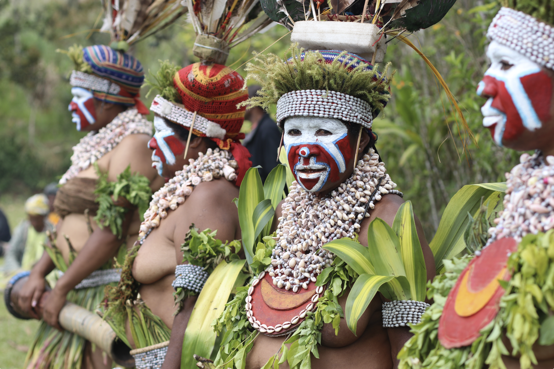 Women in traditional dress adorned with face paint, shell jewelry, and feathered headdresses at the Goroka Show in Papua New Guinea, celebrating the region’s vibrant cultural heritage.