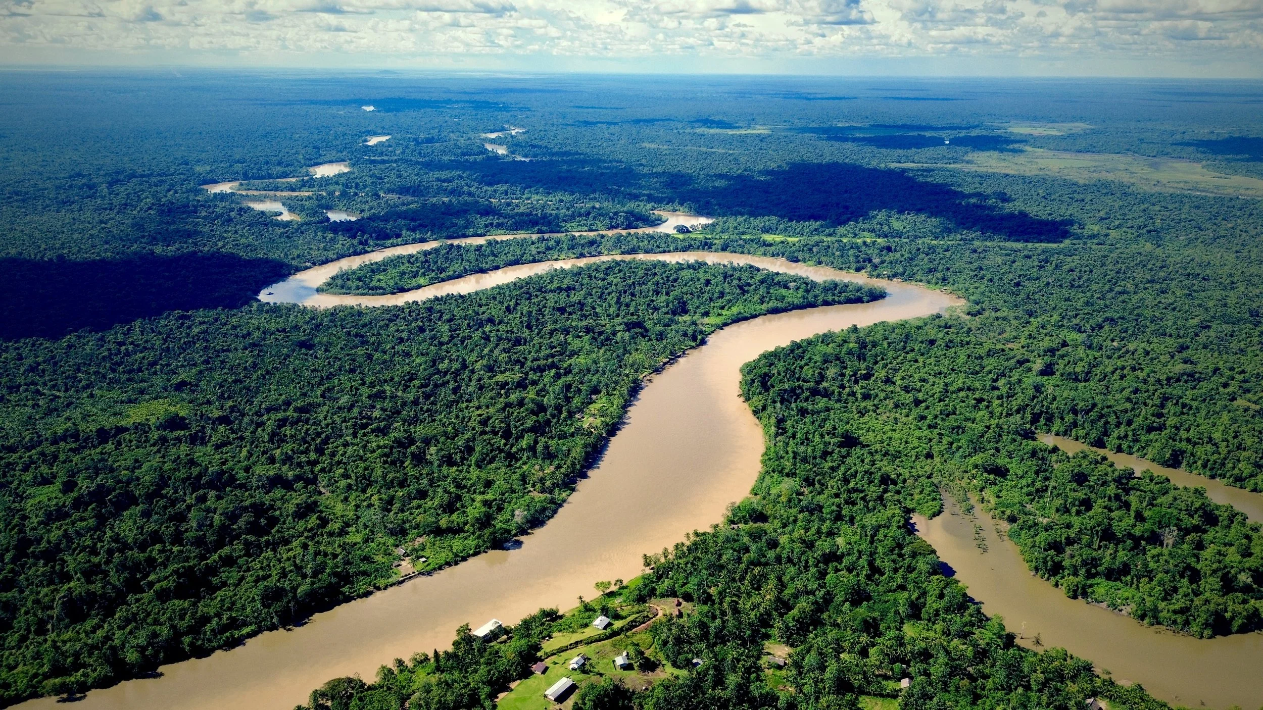 Aerial view of the winding Sepik River cutting through dense tropical rainforest in Papua New Guinea, with scattered villages nestled along the riverbanks