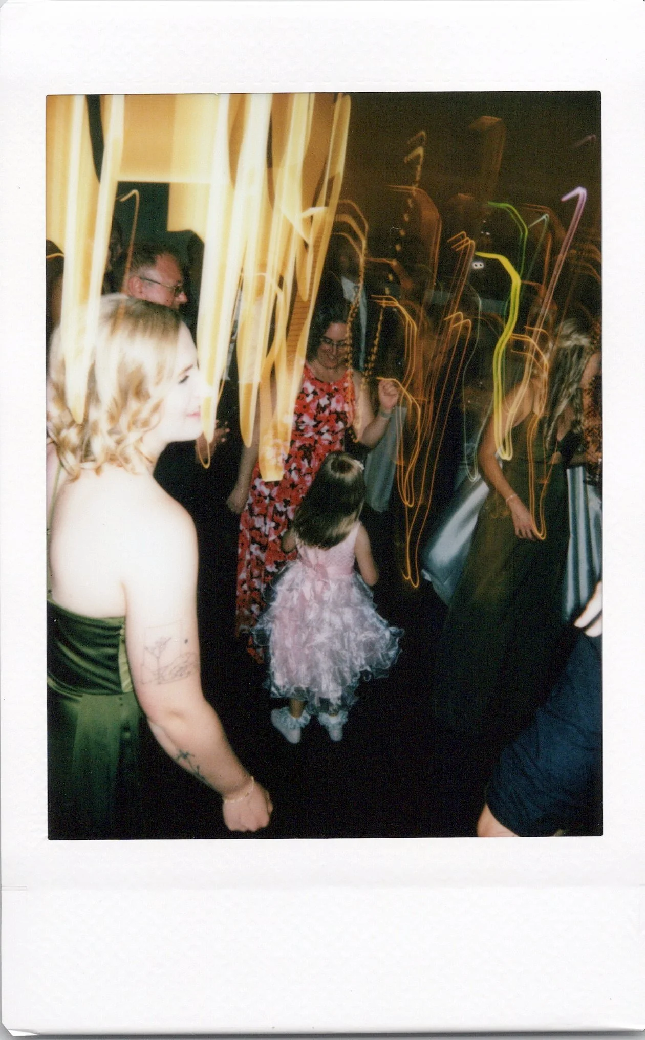 People dancing at a party or celebration night, with light trails from movement in a dark indoor setting.