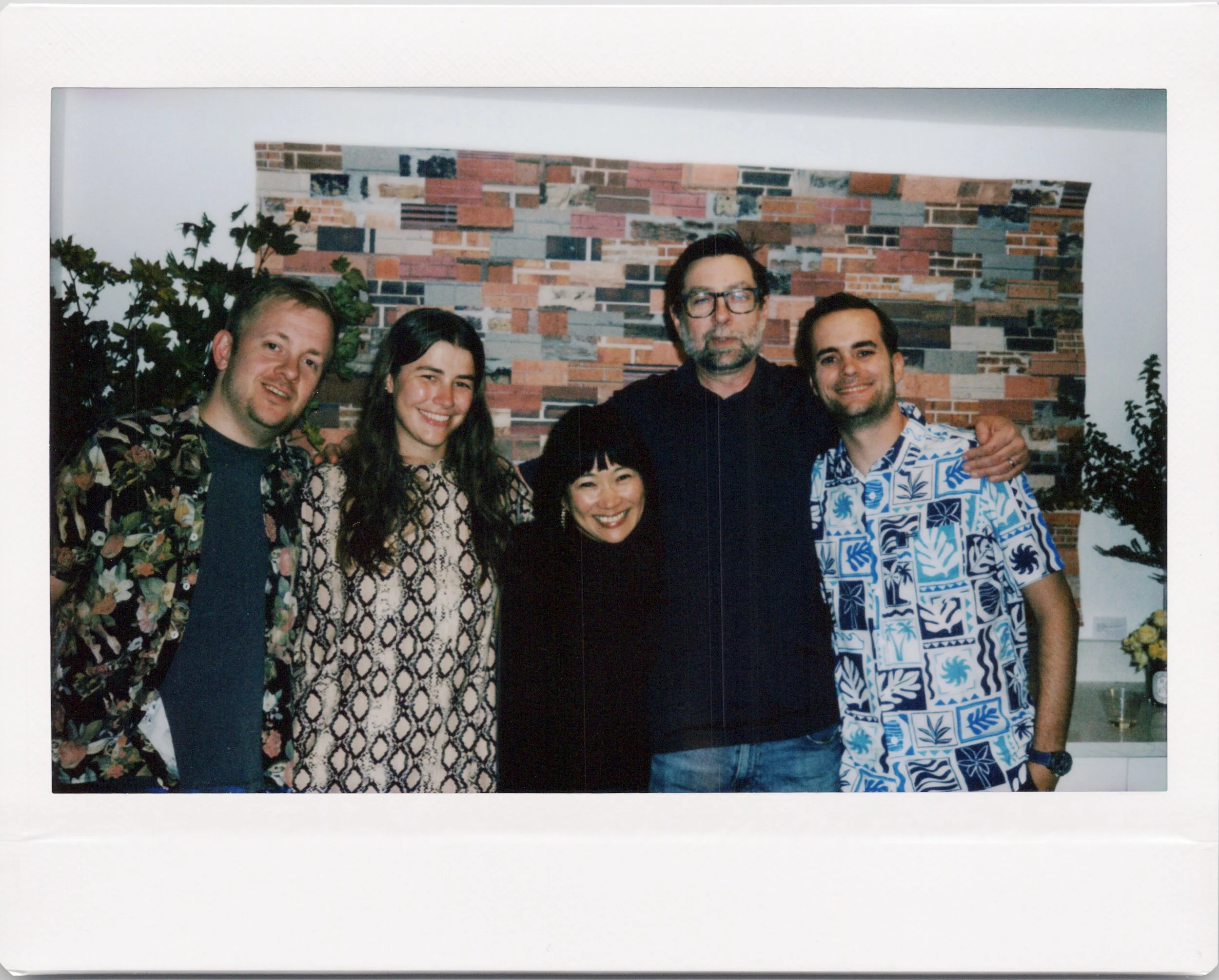 Instax Wide polaroid onsite photo of guests posing in front of a brick quilt art piece by Mark Hawk a Chicago artist and Photographer
