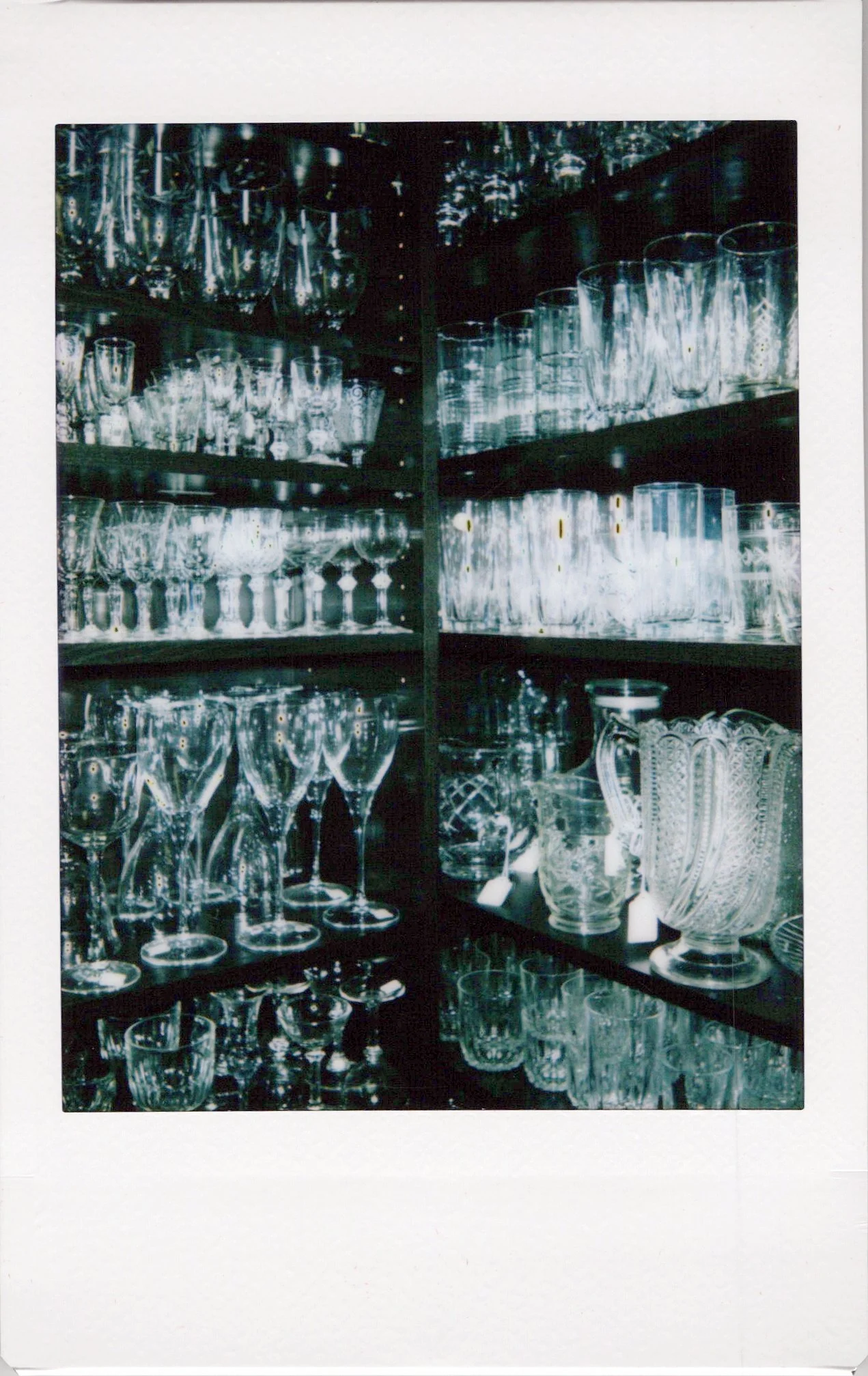 A display of various glassware, including wine glasses, tumblers, and decorative vases, arranged on shelves.