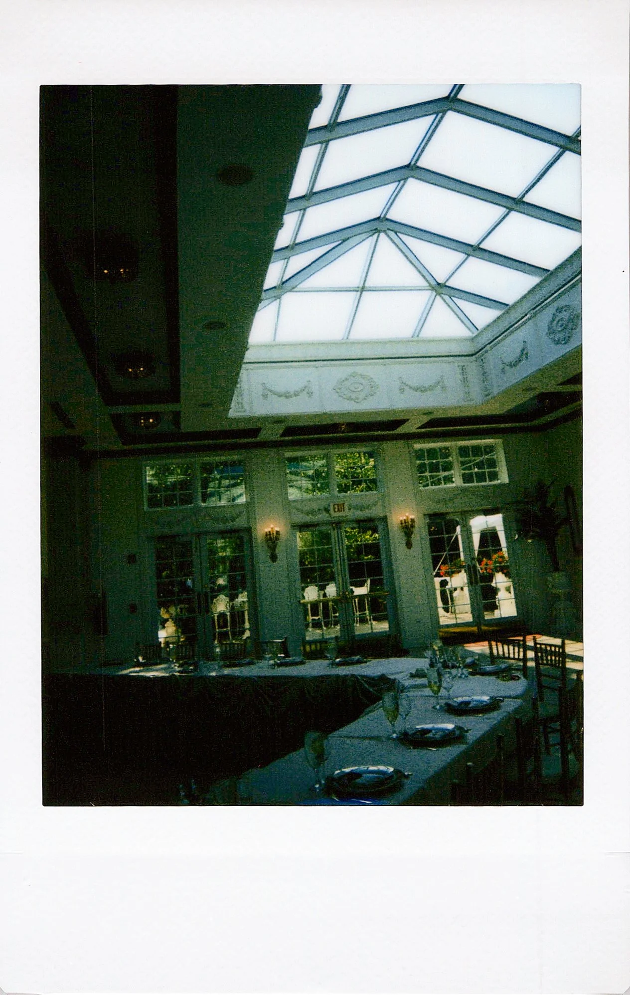 Indoor dining area with a glass pyramid skylight ceiling, set up for a meal with tables, chairs, and place settings.