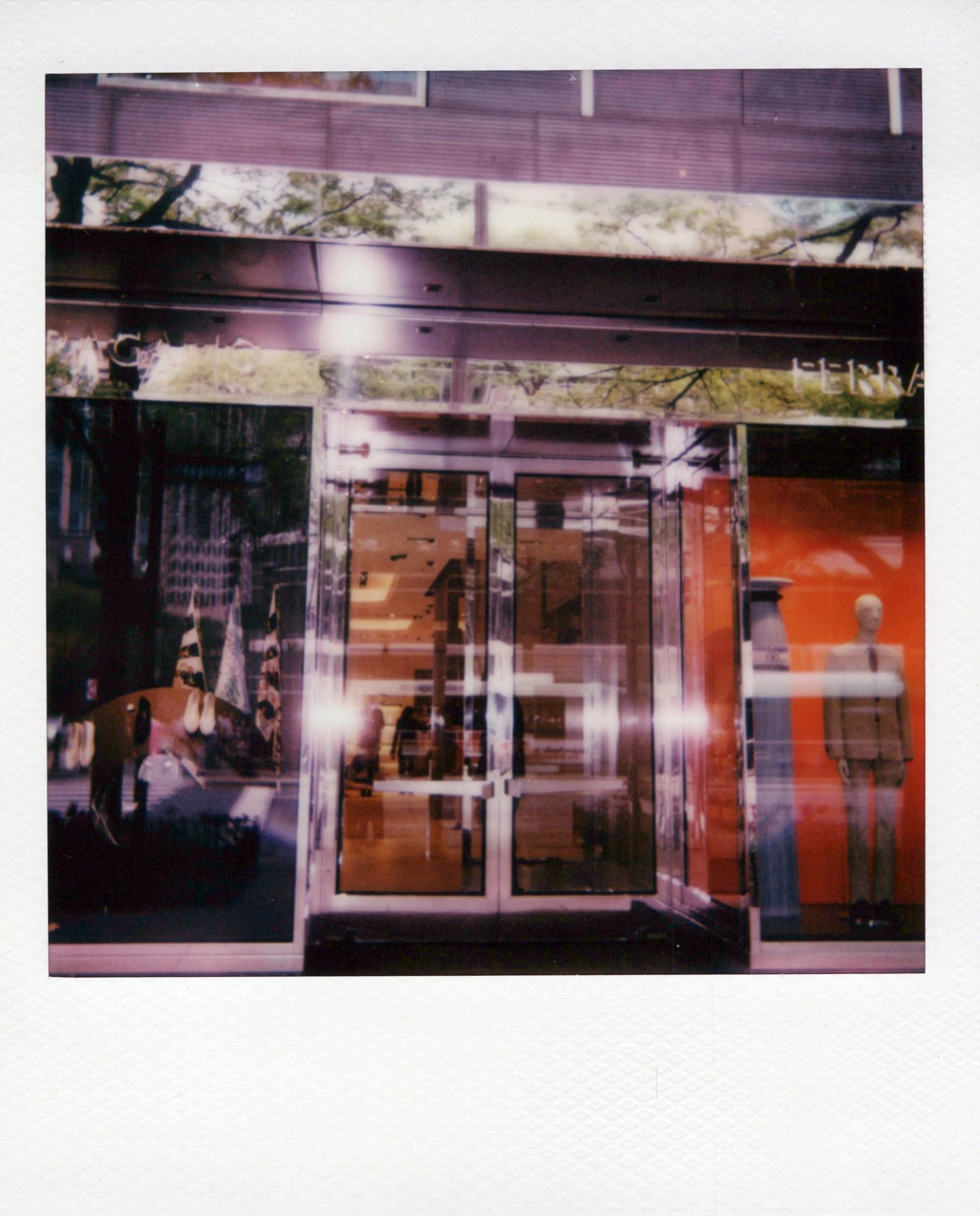 A Polaroid picture showing a Ferragamo boutique with steel beams and wooden panels, and a mannequin bust with a white head and shoulders in the foreground.