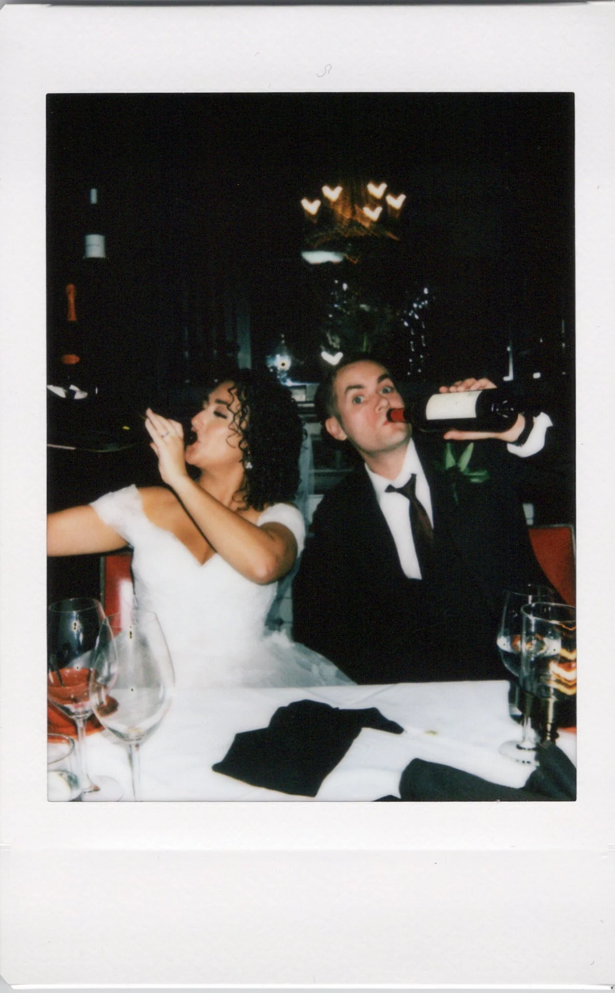 Instant photo onsite of bride and groom drinking wine at reception.