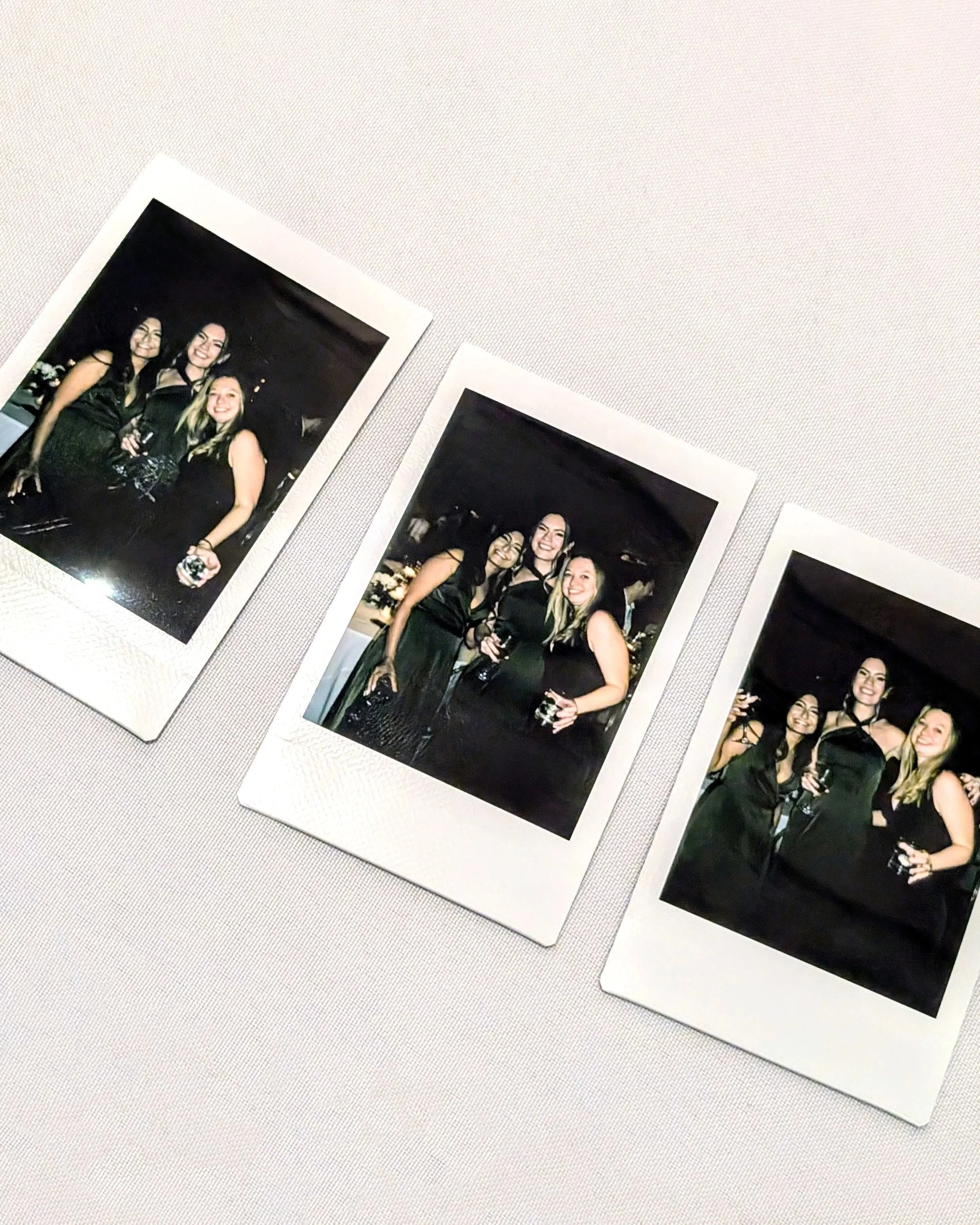 three instant photos for guests at a wedding, they are each wearing dark green dresses and smiling for the camera