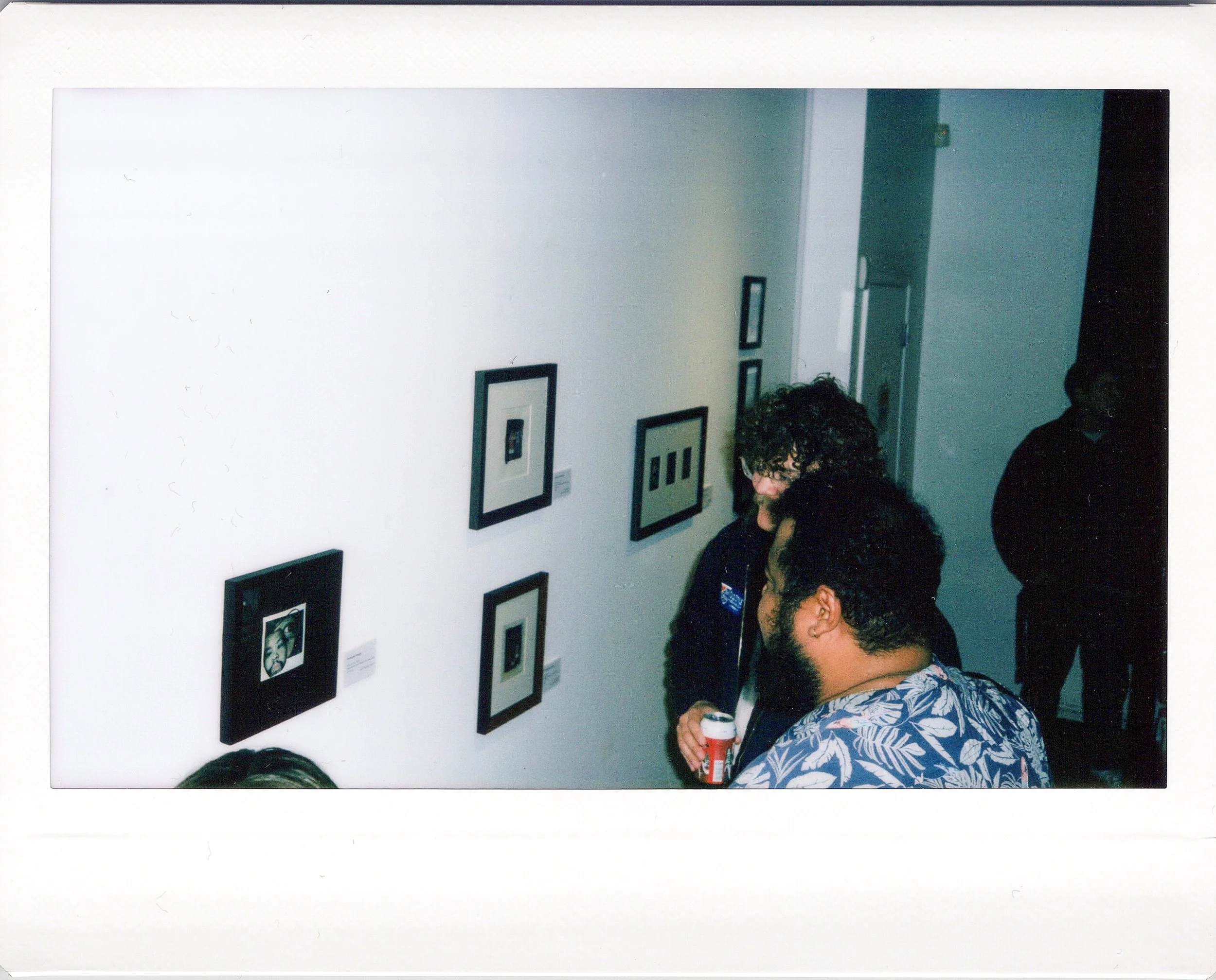 Polaroid photo of people viewing artwork in an art gallery.