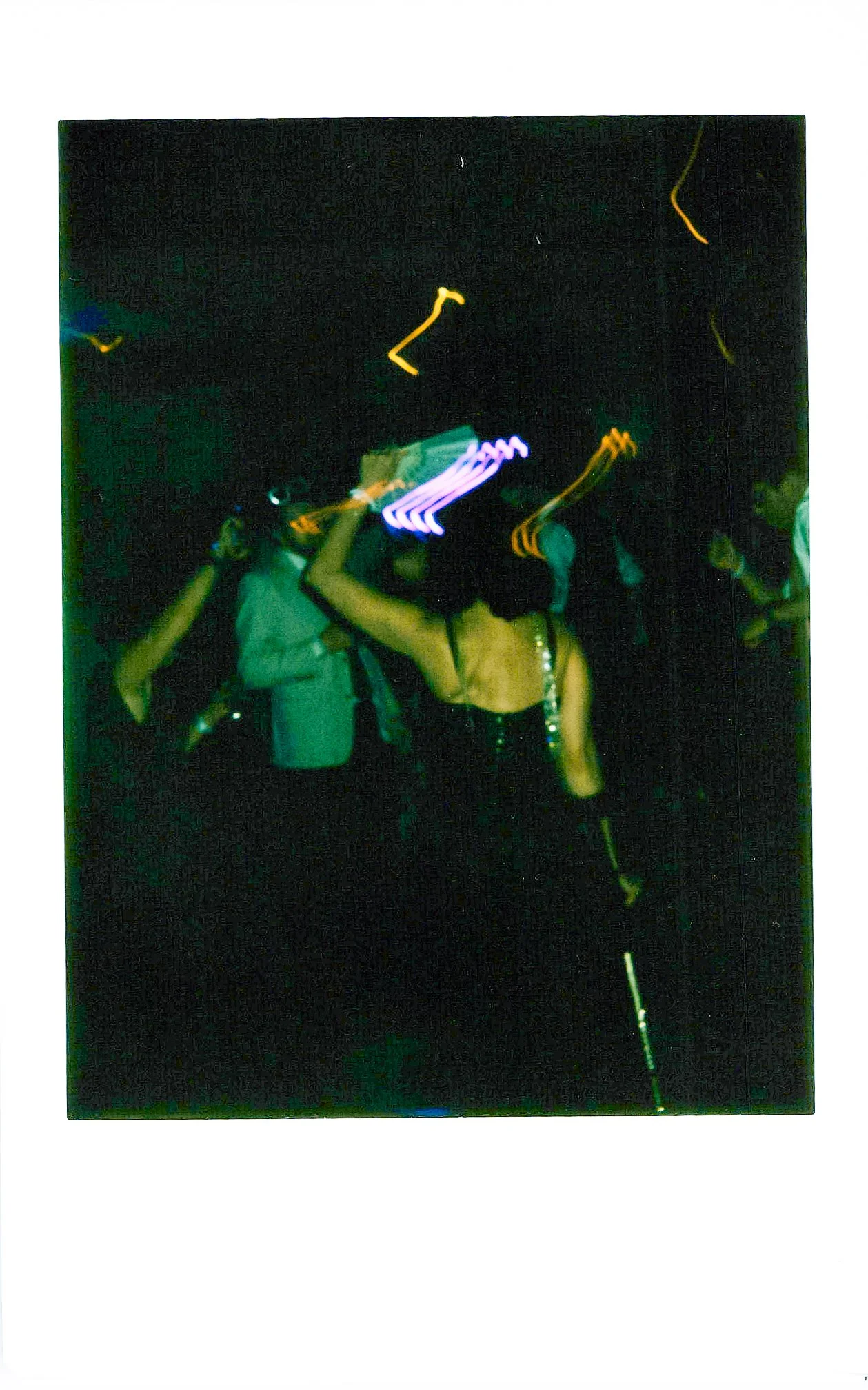 People dancing at a party with colorful lights illuminating the dark room.