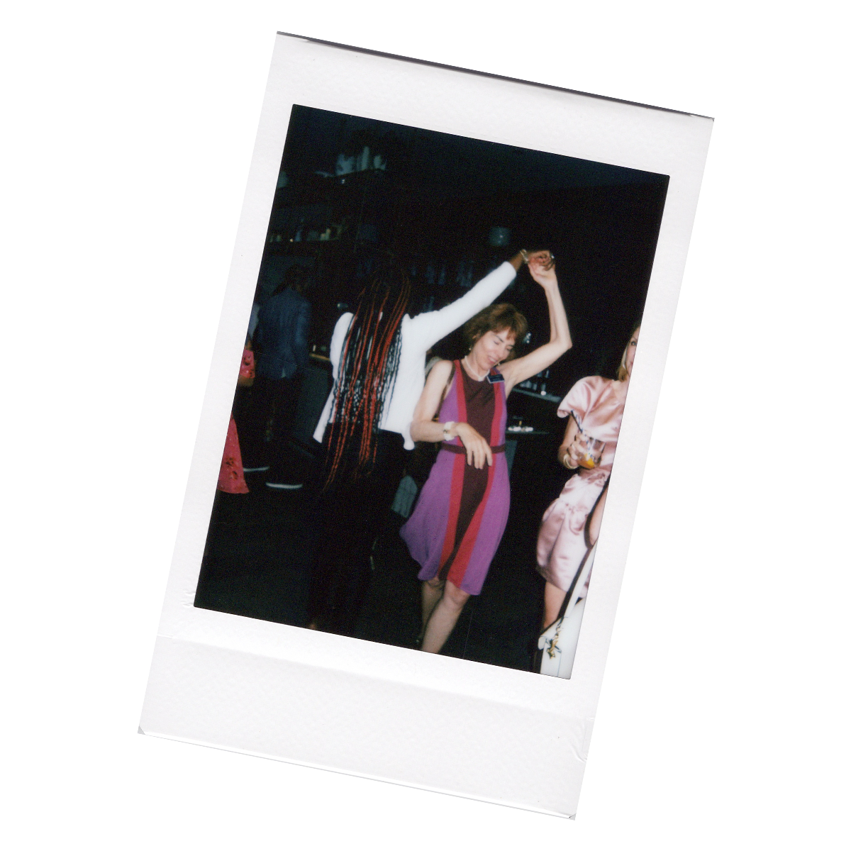 Two women dancing at a social event, one with long braids and the other with short brown hair wearing a colorful dress.