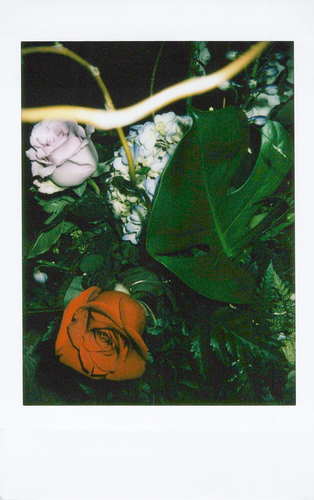 Colorful artificial flowers, including a pink peony, orange rose, white hydrangea, and greenery in a floral arrangement.