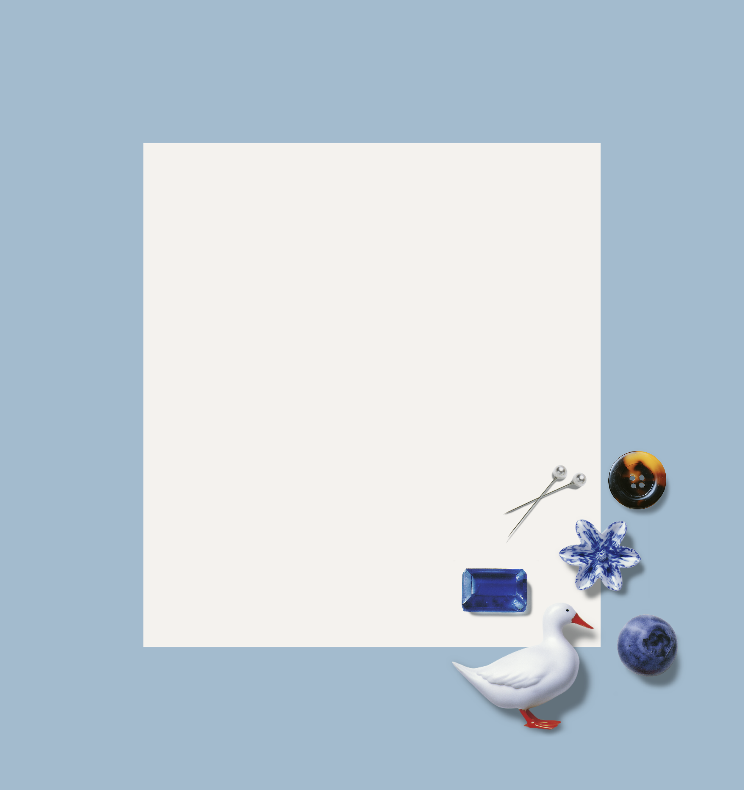 White square paper with various decorative objects around it, including a goose figurine, a blue gemstone, a blue and white flower-shaped item, a black button, a star-shaped pin, and a silver pin, set against a light blue background.