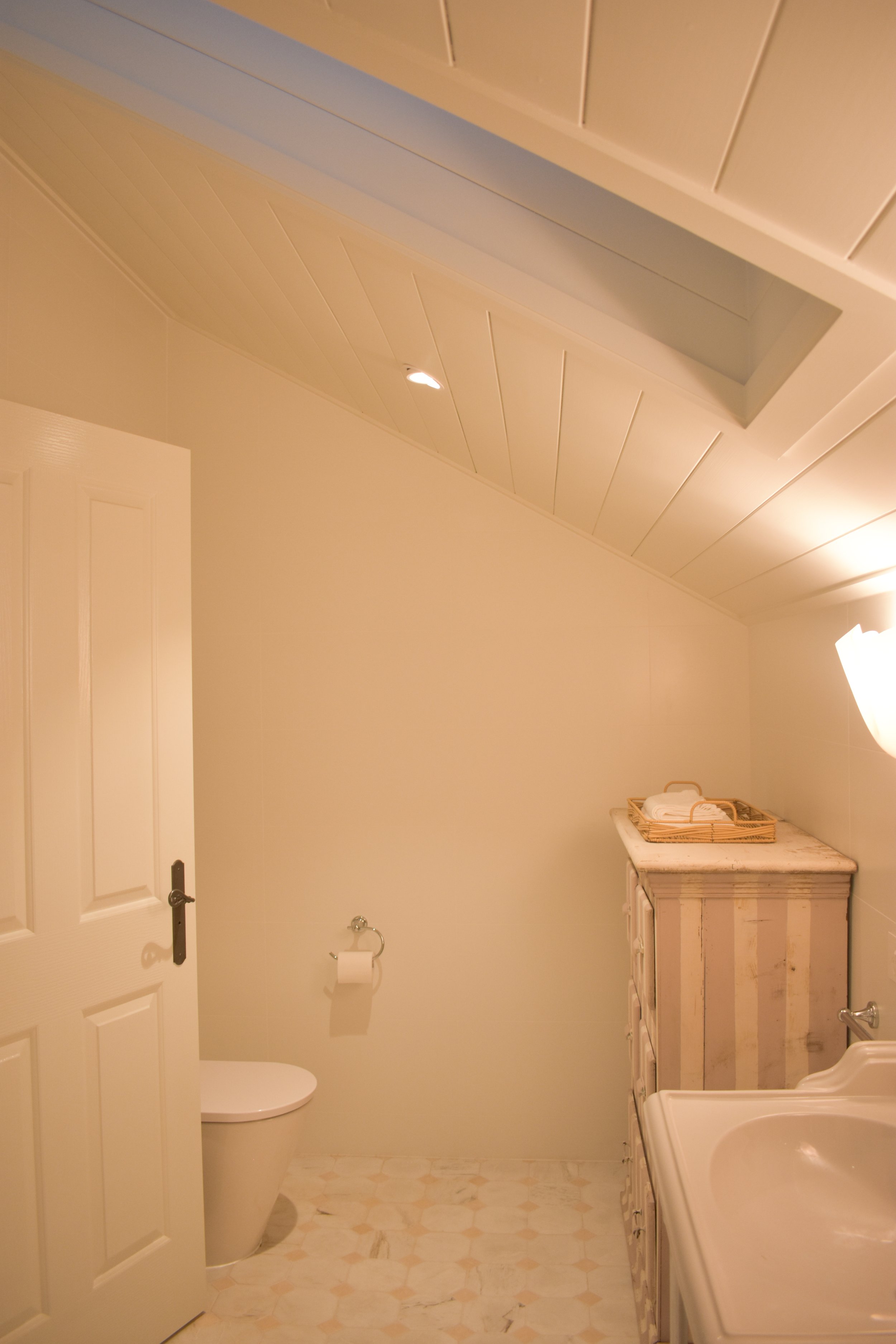 An image of the bathroom renovation with gold fittings and a skylight.