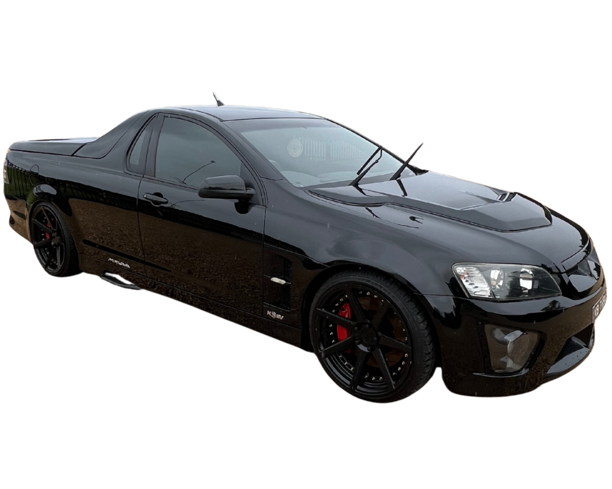 Black sports car with sporty wheels and red brake calipers, viewed from front left side.