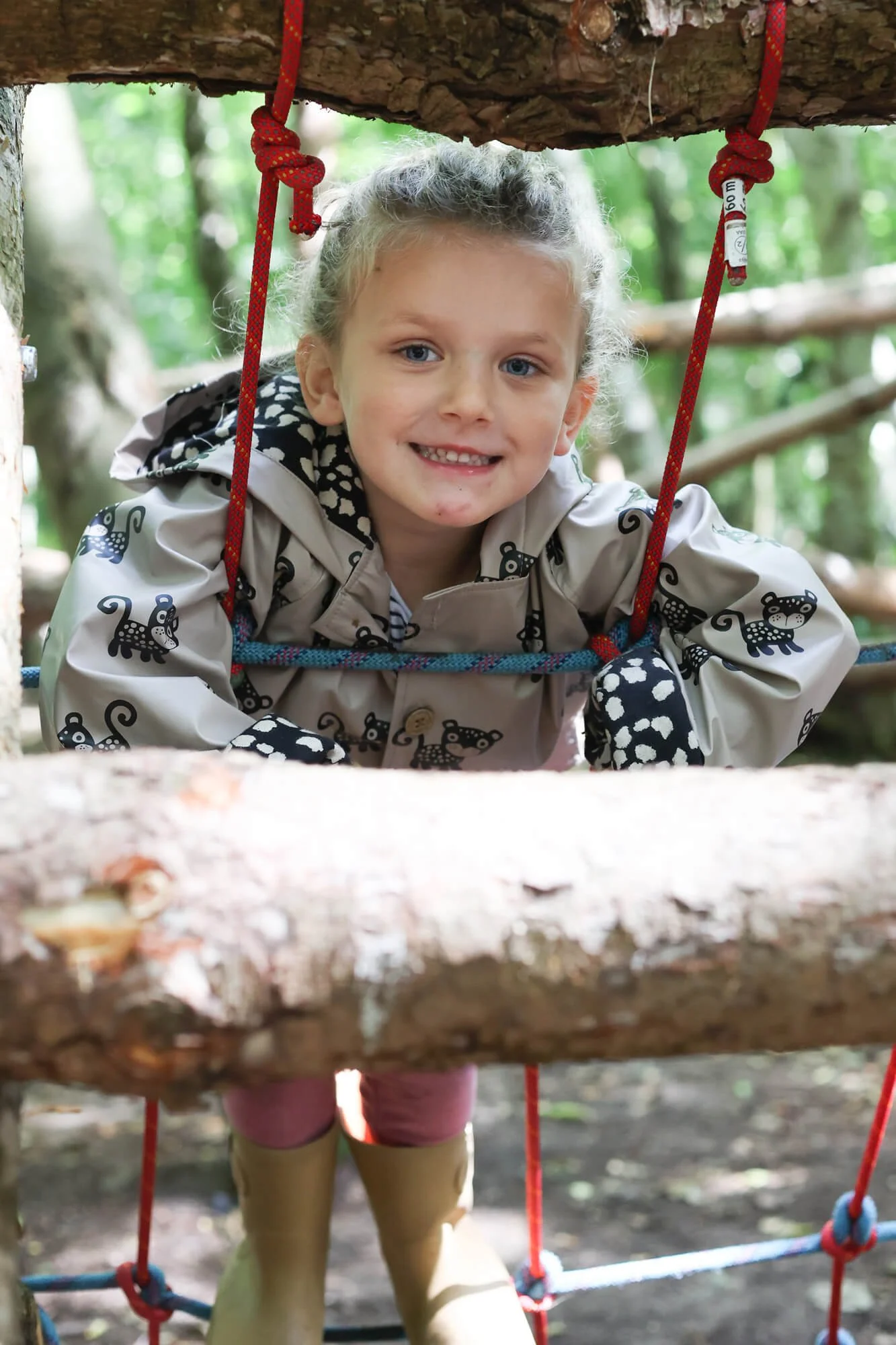 Girl smiling on a ladder attached to a tree