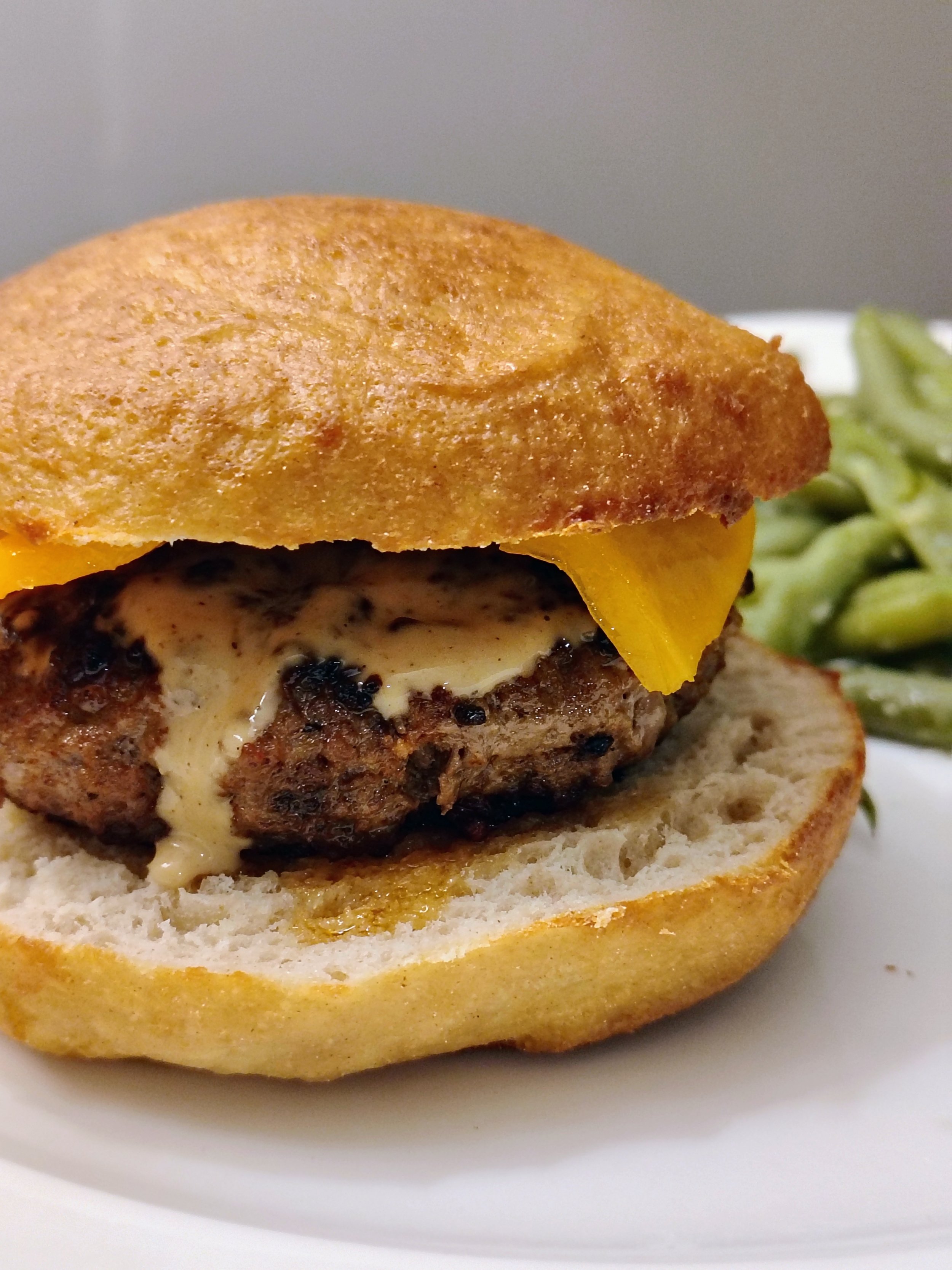 Burger with bun, cheese, and homemade sauce on a plate