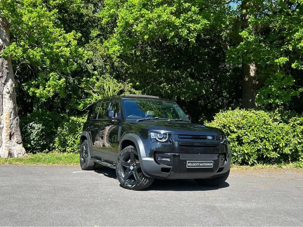 A black SUV parked on an asphalt surface with green trees and bushes in the background.