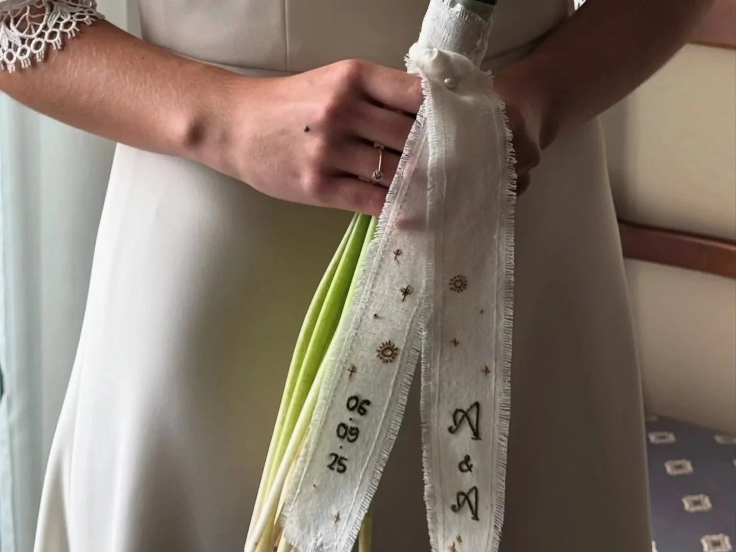 Mano con alianza sosteniendo un ramo de flores, cubierto con un velo de novia