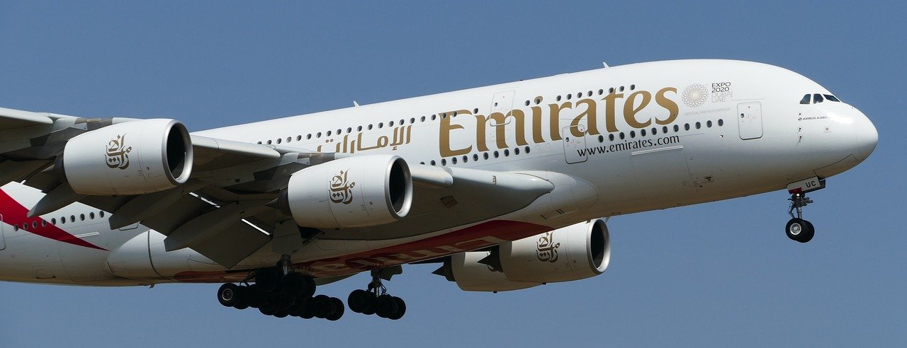 Ett Emirates-passagerarflygplan i luften, Airbus A380, mot en klarblå himmel.