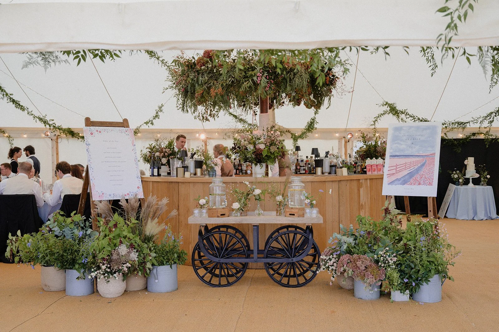 marquee bar under flower chandelier with a flower installation surrounding the bar