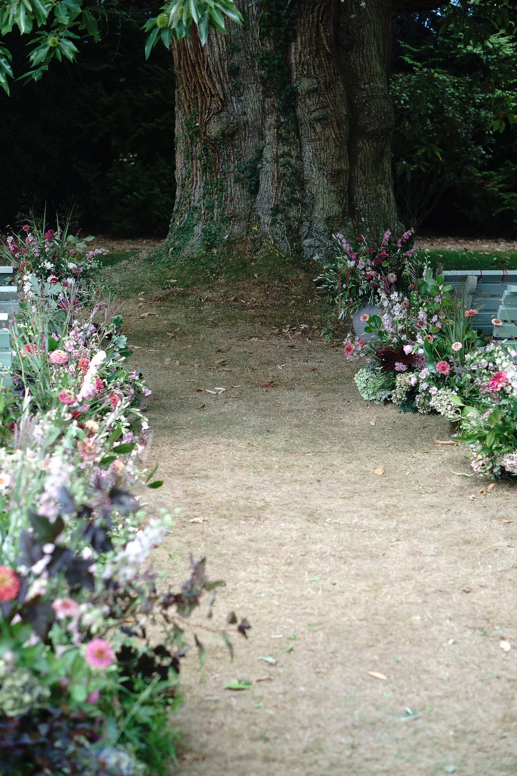 Meadow flower aisle and seasonal summer vases for outdoor ceremony at Huntsham Court