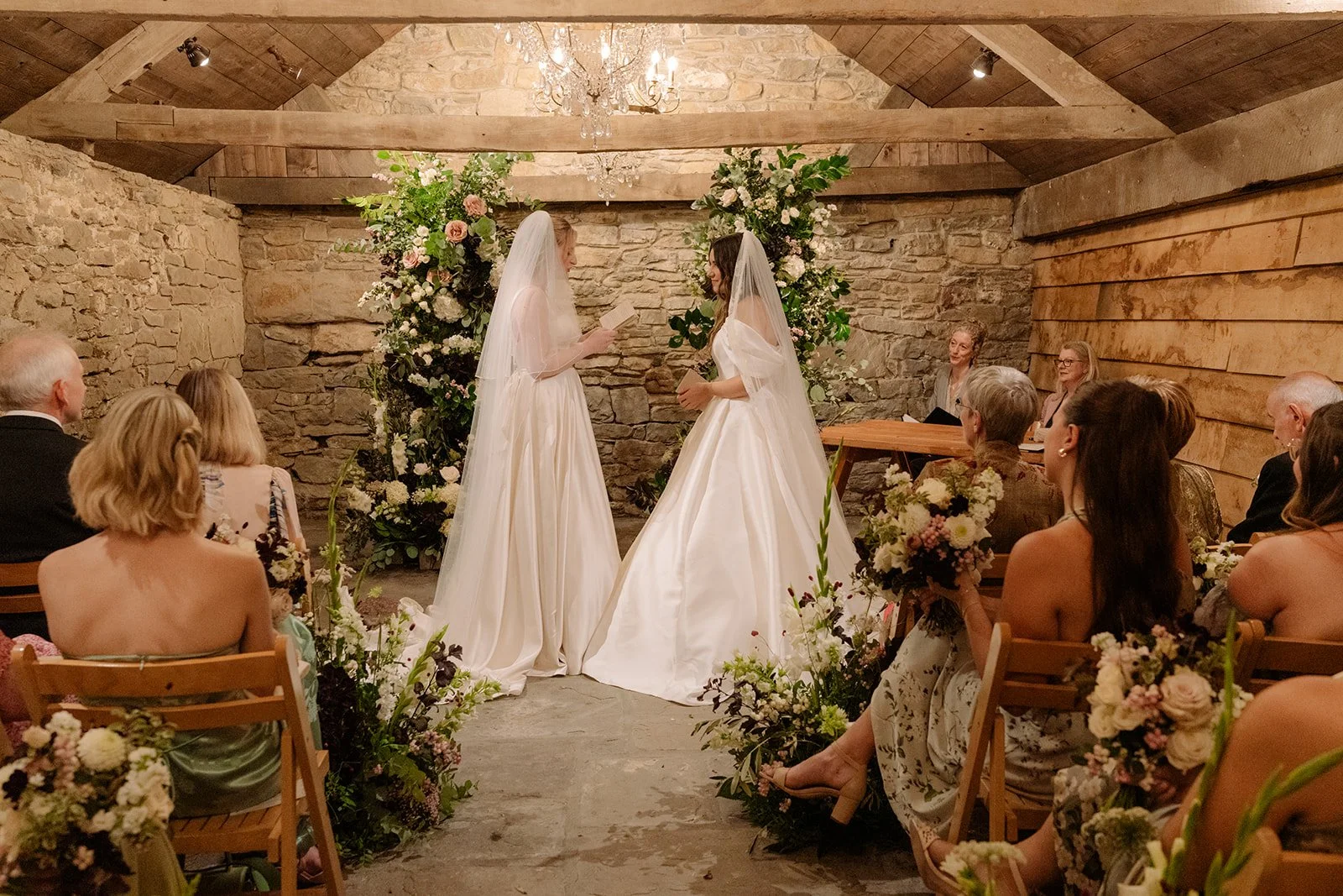 brides at Kingston estate inside wedding ceremony surrounded by natural broken flower arch and aisle meadow