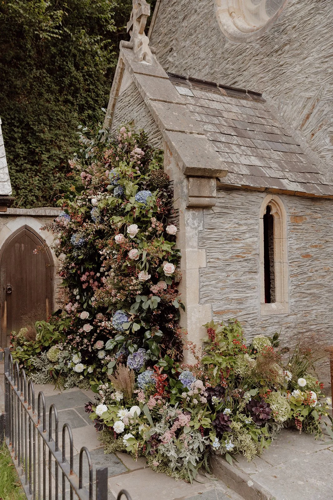 statement church flower arch at entrance of local Devon church full of British flowers and foliage