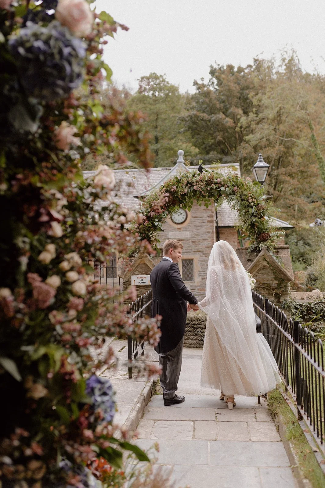 bride and groom walking through flower arch in north Devon Lee Bay church