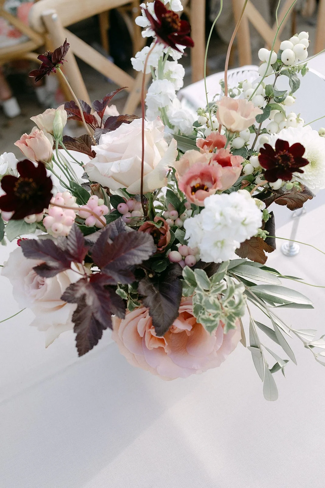 mocha, ivory and deep burgundy natural table flowers with snowberries, roses and lisanthus in ceramic pots