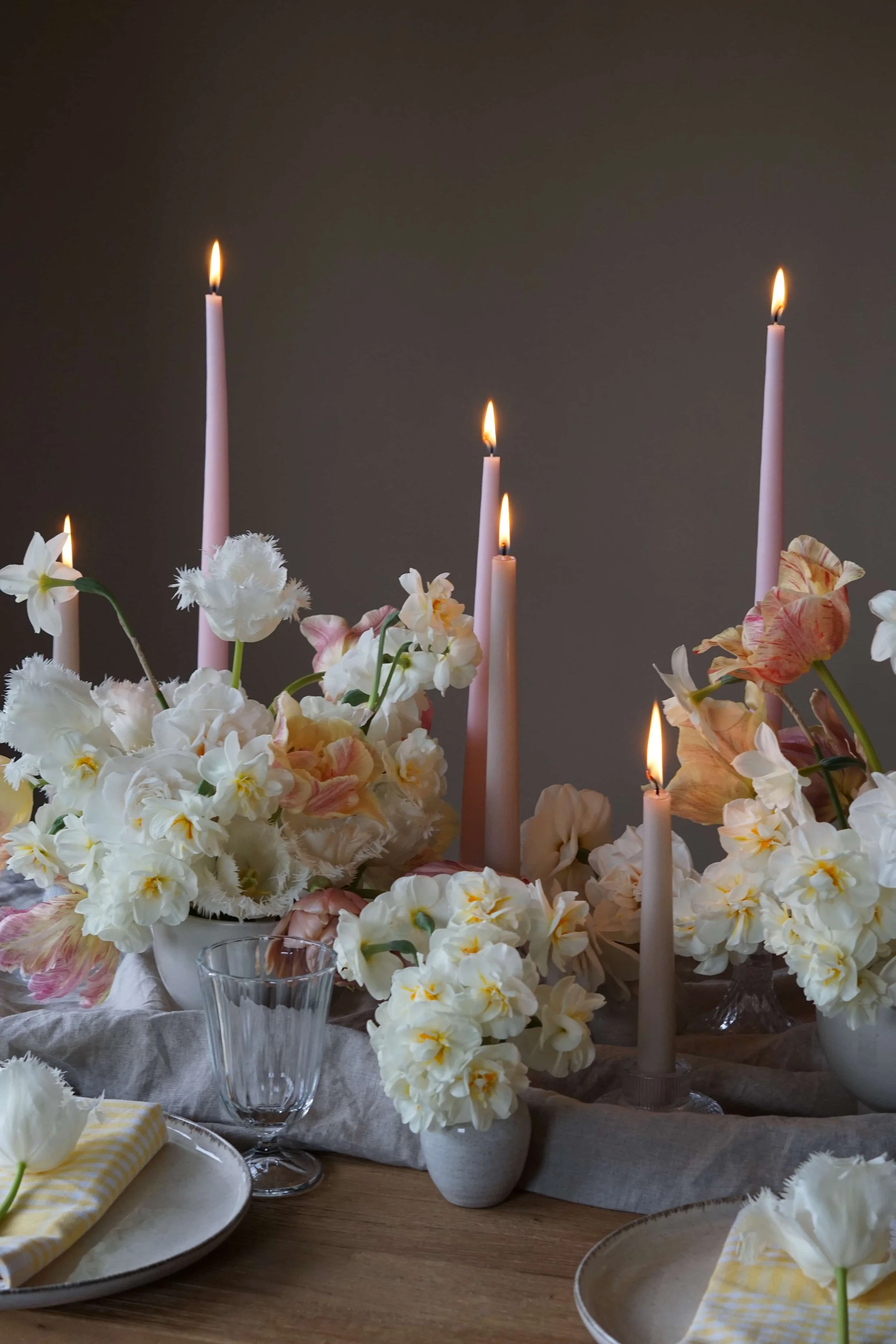 Easter tablescape of spring flowers and coloured candles with gingham napkin