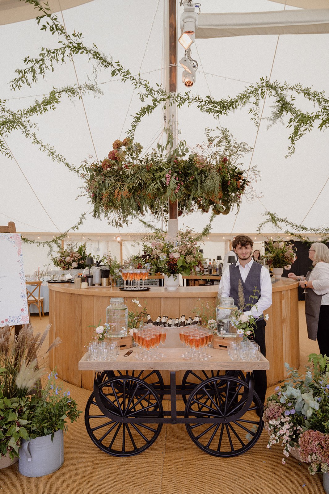 statement flower chandelier surrounding marquee bar with drinks cart in Croyde marquee
