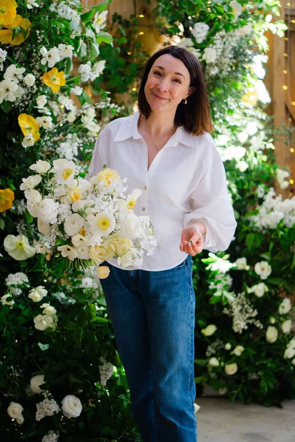 wedding florist The Rose Shed holding butter yellow bridal bouquet in front of broken flower arch