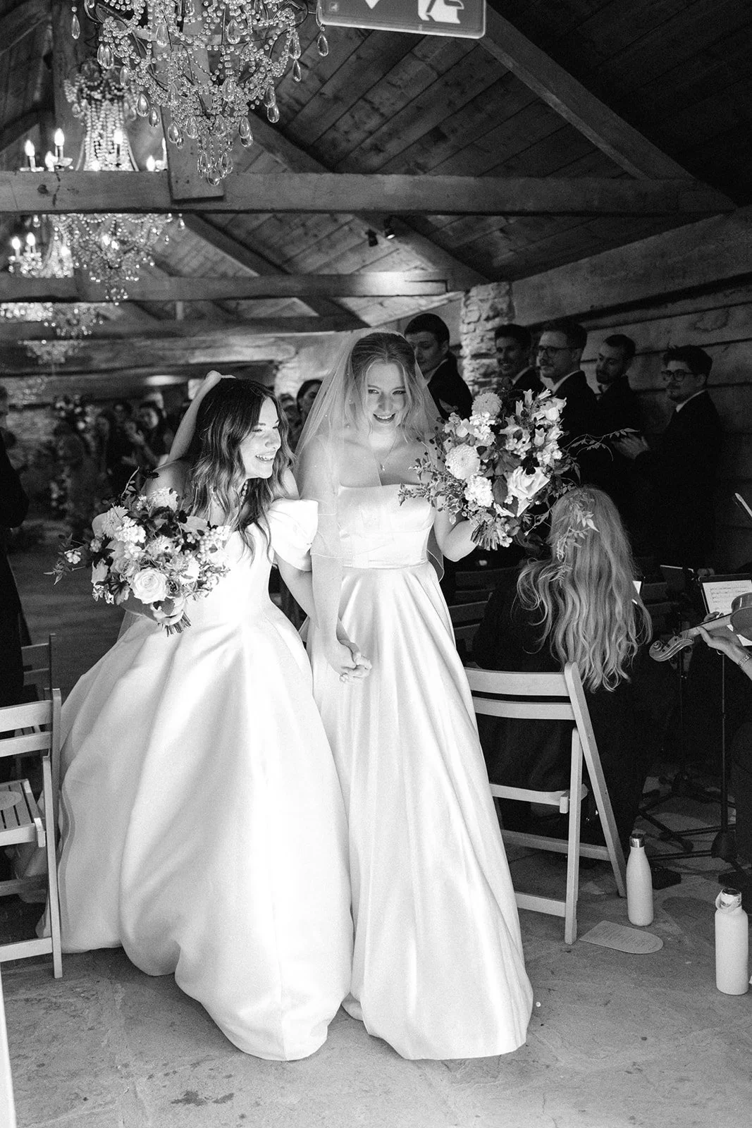 two brides just married in beautiful white dresses carrying summer. natural bridal bouquets