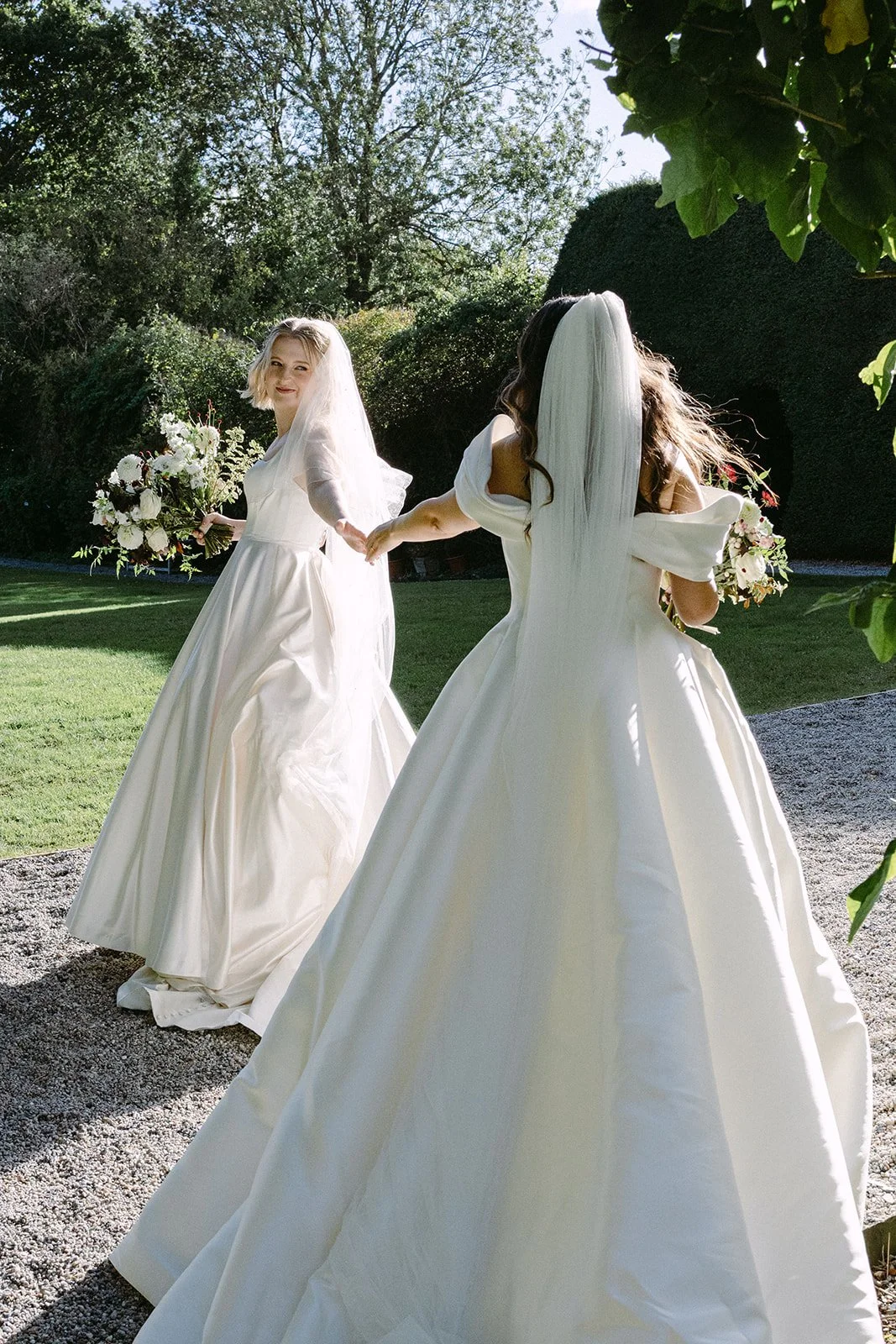 two brides wearing beautiful wedding dresses holding natural and stylish late summer wedding bouquets