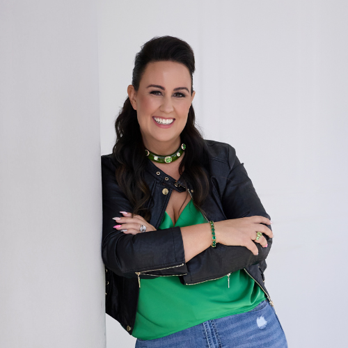 Lou Clarke leaning on wall, smiling, wearing a black leather jacket
