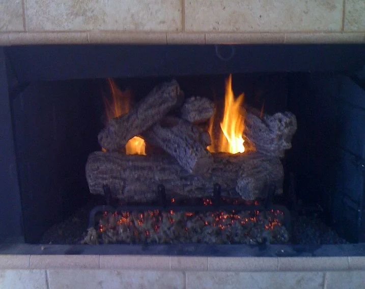 Gas fireplace with artificial logs burning