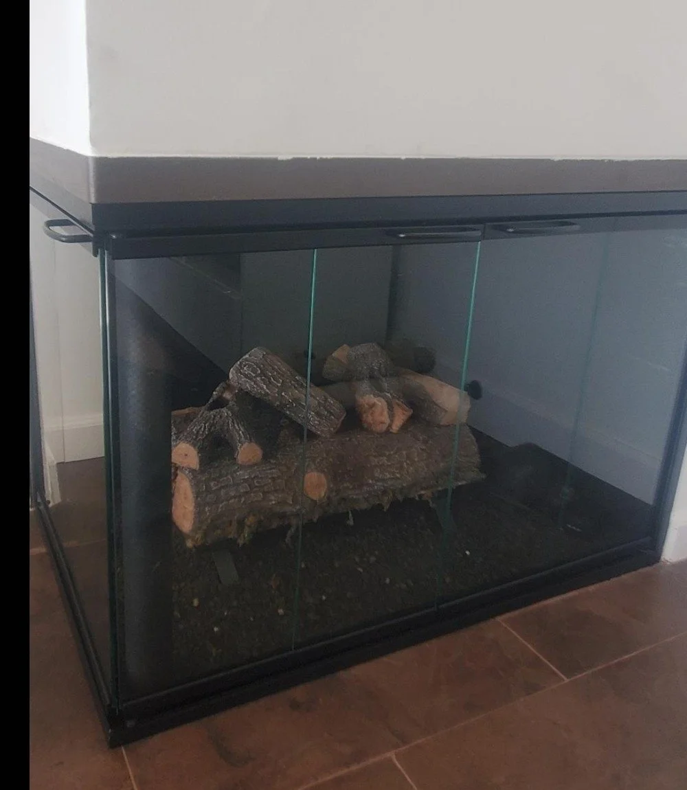 A glass terrarium with a log and sticks inside.